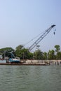 Large water crane on a river. Industrial riverbank with a water crane and beautiful nature. Riverbank full of concrete pillars.