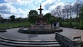 Large water fountain in the park against a backdrop of steps, grass, and trees