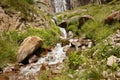 Large waterfall in middle of rocks, high mountains and water flowing among stones Royalty Free Stock Photo