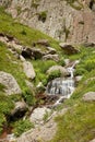 Large waterfall in middle of rocks, high mountains and water flowing among stones Royalty Free Stock Photo