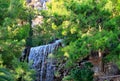 A large waterfall with radon water among boulders and thickets of spruce at the foot of a mountain in Loutraki, Greece