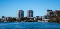 Large waterfront apartment condominiums in suburban community on harbour with tree lined walkway, blue sky in background