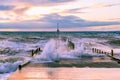 Large wave splashes protruding through boat jetty on ocean coastline.