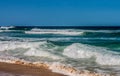 Large waves rolling in to the beach from a turqoise sea under a blue sky