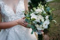 A large wedding bouquet in the hands of a beautiful bride of white and milk roses