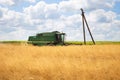 Large wheat field harvesting by a combine harvester. Sunny day. Agriculture Royalty Free Stock Photo