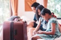 Large wheeled suitcase standing on the floor in the hotel room with happy asian family sitting on the bed in background Royalty Free Stock Photo