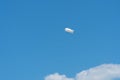 Large white air balloon in shape of an airship in the blue sky