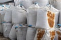 Large white bags with blue ribbon inside the salt lie on the street. Industrial fertilizers are stored in bags in a heap.