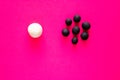 Large white ball separated from many smaller black balls. Plasticine toys, concepts of racism, white privilege and diversity. Pink