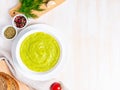 Large white bowl with vegetable green cream soup of broccoli, zucchini, green peas on white background, top view, copy space Royalty Free Stock Photo