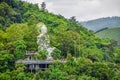 A large white Buddha stutue is enshrined on a cement courtyard in a mountainous area surrounded by green trees in Myanmar