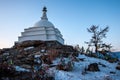 A large white Buddhist stupa against a blue sky and many colorful ribbons on bushes on the sacred island of Ogoy on Lake Baikal. Royalty Free Stock Photo