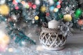 Large white candle in a wicker holder under a Christmas tree. Christmas holiday design. decorated with garlands and glittering Royalty Free Stock Photo