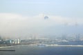A large white cloud fell on the city and closed the view of the building. Foggy cloud moves from the sea to the city. Royalty Free Stock Photo