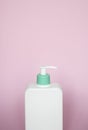Large white cosmetic plastic bottle with pump dispenser pump and green cap on pink background. Liquid container for gel Royalty Free Stock Photo