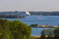 Large white cruise liner swims between picturesque islands