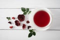 A large white cup with fragrant hibiscus rose petal tea on a white wooden background with rose petals and leaves. top view Royalty Free Stock Photo