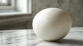 Large white egg placed on a marble surface with soft lighting in a minimalistic setting Royalty Free Stock Photo