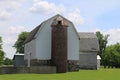 A large white farm barn and stone foundation and silo with green grass lawn and trees Royalty Free Stock Photo