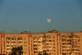 Large white full moon on clear blue over an urban city high building Royalty Free Stock Photo