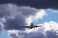 A big white airplane flying in the blue sky with many white and dark blue clouds Royalty Free Stock Photo