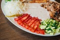 Large white plate with a selection of snacks and creamy sauce. Baked tortillas, tomatoes with cucumbers and cheese. Dark meat with Royalty Free Stock Photo