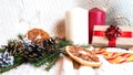 large white and red candles, dried orange slices, golden fir cones, a Christmas caramel cane and a gift box in eco paper