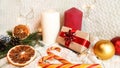 large white and red candles, dried orange slices, golden fir cones, a Christmas caramel cane and a gift box in eco paper
