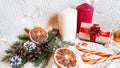 large white and red candles, dried orange slices, golden fir cones, a Christmas caramel cane and a gift box in eco paper