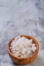 Large white sea salt in a natural wooden bowl on light background, top view, close-up, selective focus Royalty Free Stock Photo