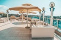 Large white umbrella and outdoor furniture sofas and rattan chairs with cushions and a glass-topped table. Place to relax on the Royalty Free Stock Photo