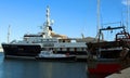 A large white yacht and a small boat parked in the seaport