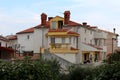 Large white and yellow Mediterranean villa with multiple balconies on each side surrounded with fig trees and other garden