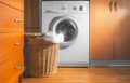 Large Wicker Laundry Basket, Lid Opened, Near the Front Load Washing Machine with Laundry. House Interior Laundry Room. Wood Royalty Free Stock Photo