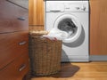 Large Wicker Laundry Basket, Open Lid Near the Washing Machine with Laundry. House Interior Laundry Room. Wood Interior Design