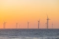 Large wind turbines producing plant on sea under sunset