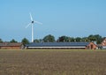 Large windmill behind cattle shed with solar modules on the roof. Paderborn