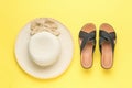 A large women`s hat and black summer sandals on a yellow background. Minimal summer concept