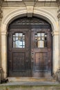 Large wooden arched gates with lots of detailing, set into a stone wall