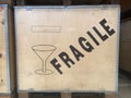 a large wooden box with metal reinforced corners with a fragile message and a cup symbolizing the delicate shipping, logistics and