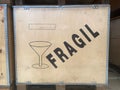 a large wooden box with metal reinforced corners with a fragile message in Spanish and a cup symbolizing the delicate shipping,