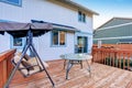 Large wooden deck with swinging bench, and glass table.