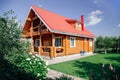 Large wooden newly built country house with red tile roof, lawn area on right and cherry trees orchard behind house and Royalty Free Stock Photo