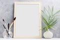 Large wooden Photo frame mock up with green palm leaves in vase and brushes in glass on shelf. Scandinavian style Royalty Free Stock Photo