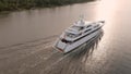 A large yacht moves along the coast at sunrise