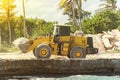 Large yellow bulldozer with jack hammer on construction site against background of palm trees. construction of a hotel on island Royalty Free Stock Photo