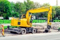 Large yellow excavator digs a hole, repairs the road, heavy equipment, road works. Royalty Free Stock Photo