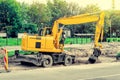 Large yellow excavator digs a hole, repairs the road, heavy equipment, road works. Royalty Free Stock Photo