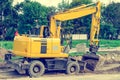 Large yellow excavator digs a hole, repairs the road, heavy equipment, road works. Royalty Free Stock Photo